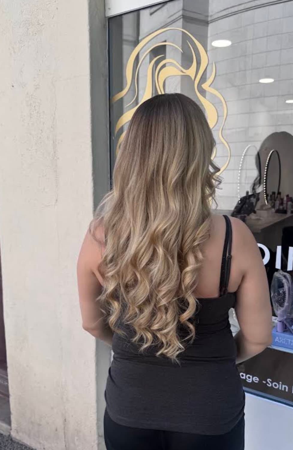 Balayage blond et brushing bouclé devant le salon SSA Coiffure